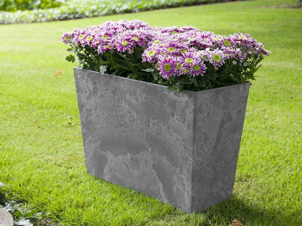 Grauer Artstone-Ella-Divider auf einer Rasenfl&auml;che, dicht mit rosa-violett bl&uuml;henden Pflanzen bepflanzt