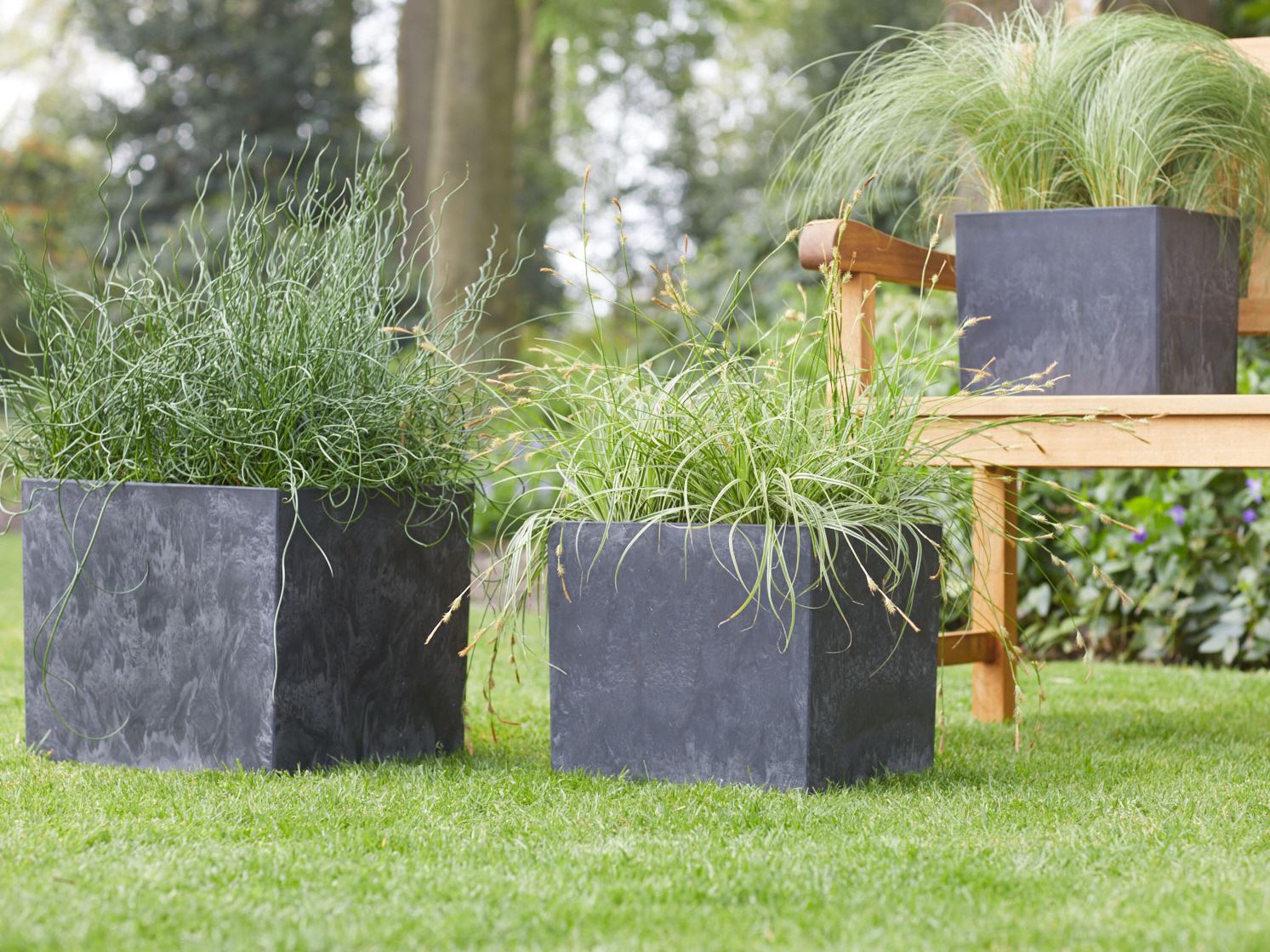 Schwarze Artstone Maud T&ouml;pfe mit Gr&auml;sern in einem Garten