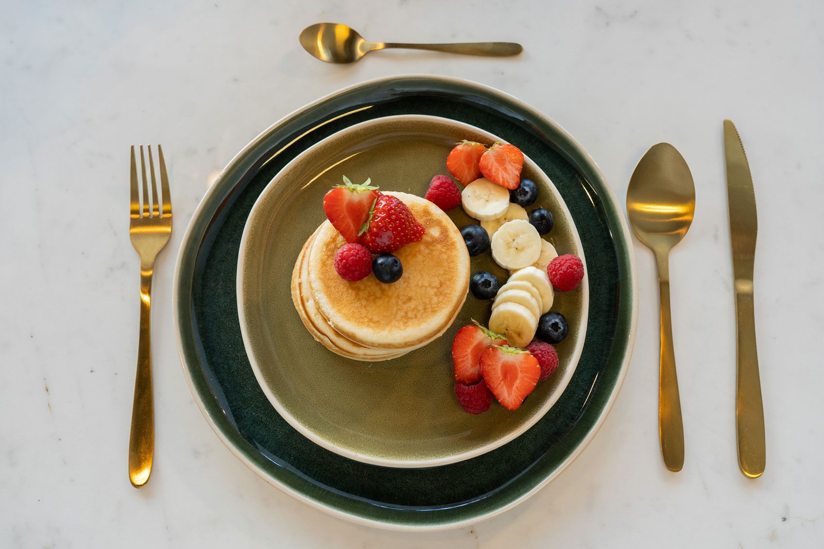 Gedeck von oben: Speiseteller Savannah Twilight mit Fr&uuml;hst&uuml;cksteller Oasis, Pancakes und goldenem Besteck